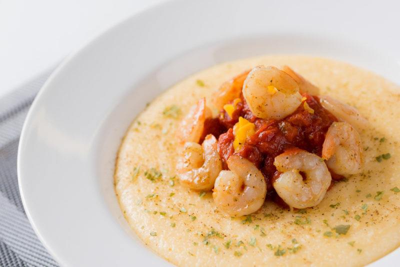 A white bowl with grits and shrimp