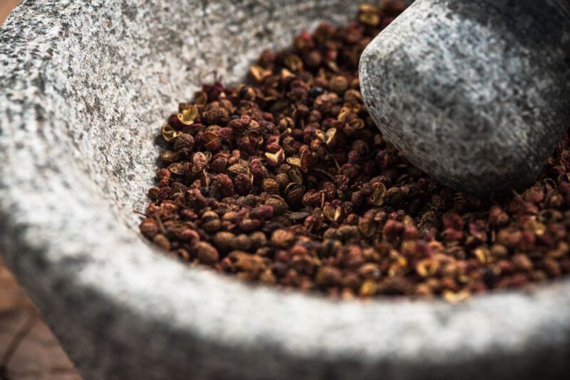 closeup image of a stone mortar and pestle with Sichuan peppercorns