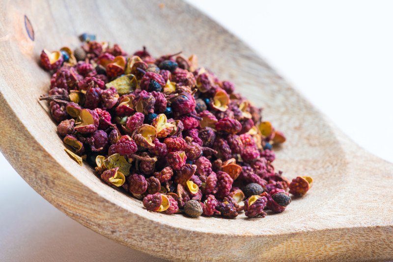 closeup image of a wooden ladle with Sichuan red peppercorns