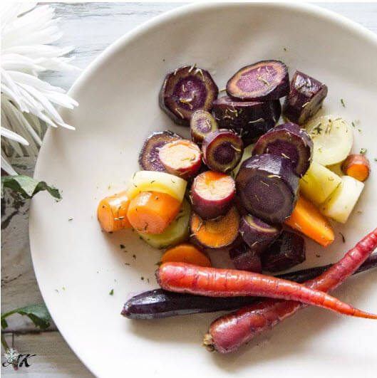 A large white plate with various carrots, some sliced and some whole. The carrots have all been cooked using sous vide. 