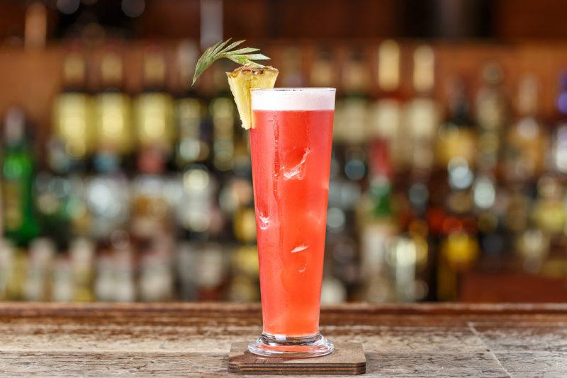 A Singapore Sling cocktail with pineapple garnish on a table