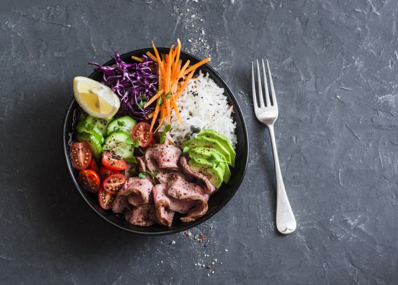 A black bowl with sliced beef, rice and vegetables