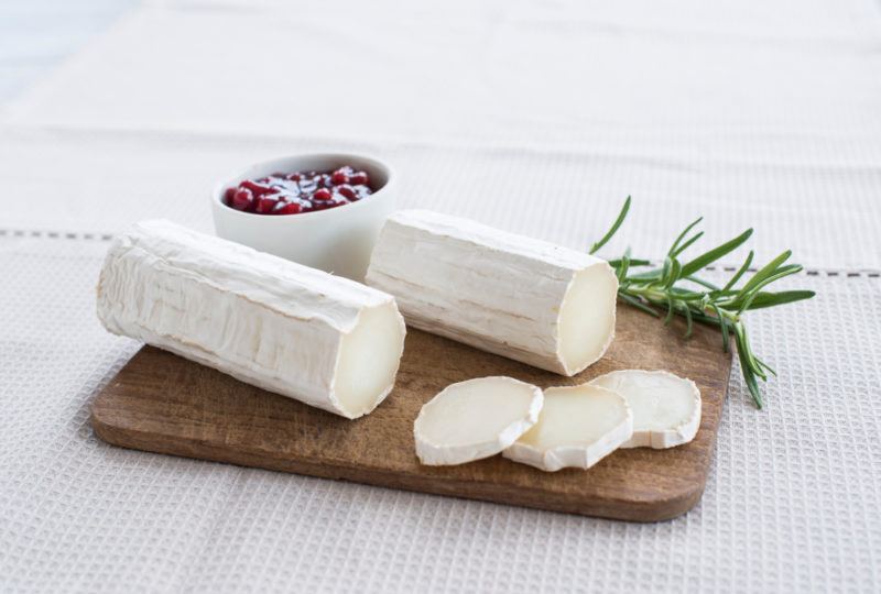 Sliced Chèvre cheese and rolls on a cutting board