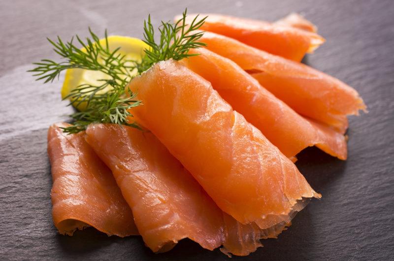 Sliced of smoked salmon on a plate with lemon and dill