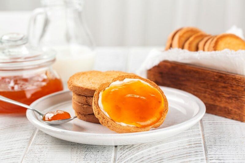 A white table with a white plate containing bread and jam