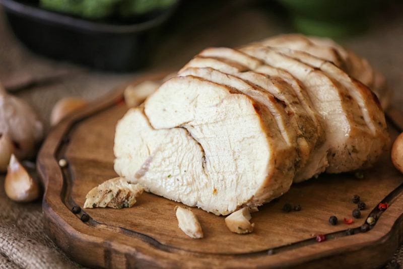 An irregular wooden board with sliced turkey breast