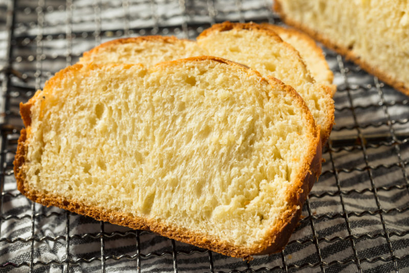 Three pieces of brioche sliced on a drying rack with the rest of the loaf in the background