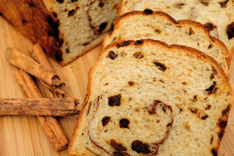 Slices of cinnamon raisin bread next to some cinnamon