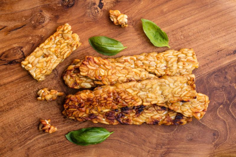 Slices of fried tempeh on a wooden board