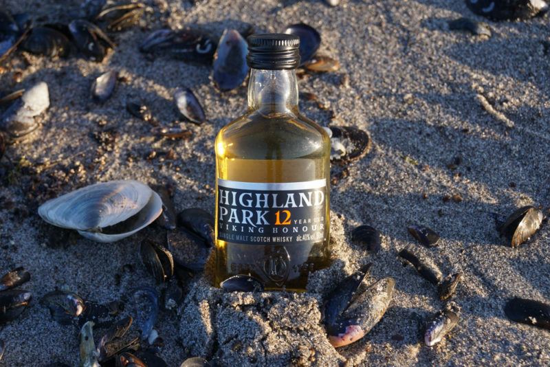 Small Bottle of Highland Park 12 Scotch sitting in beach sand