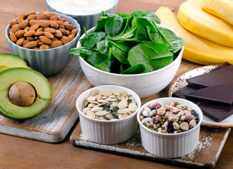 A selection of magnesium rich foods, including spinach, nuts, bananas, and avocado