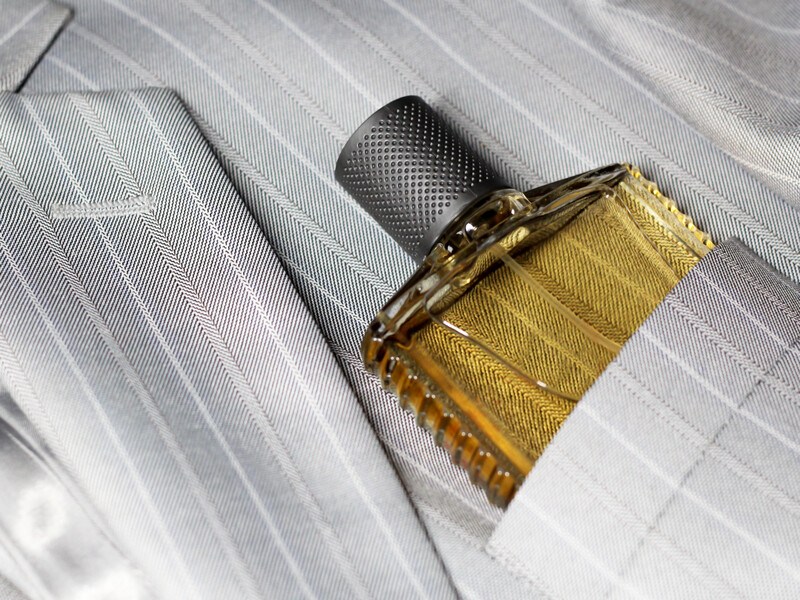 Small bottle of amber colored cologne, tucked into the front pocket of a suit coat