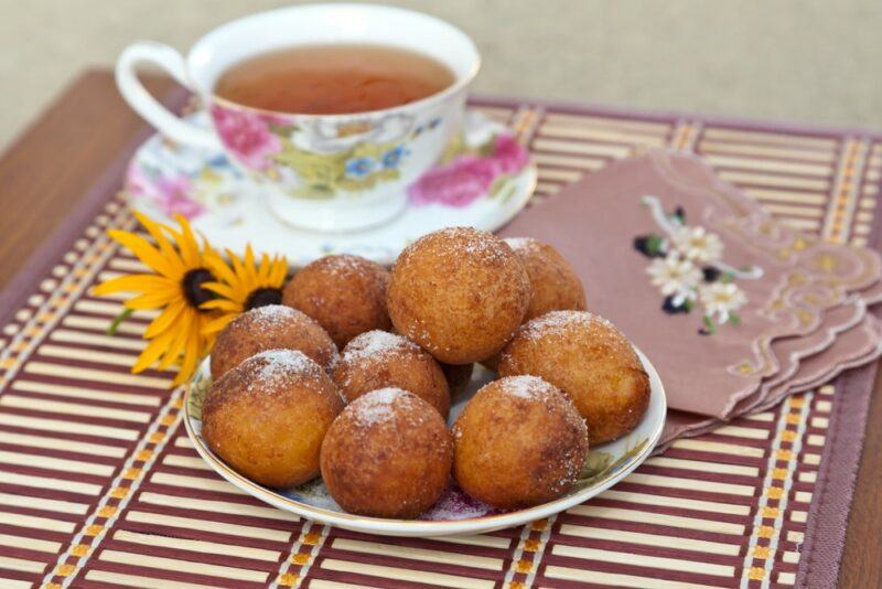 A table with Russian donut holes called Ponchiki, next to a mug of tea