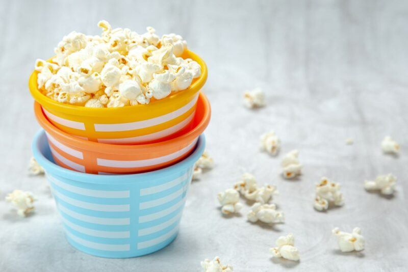 Three small pails for kids stacked, where the top one is filled with popcorn