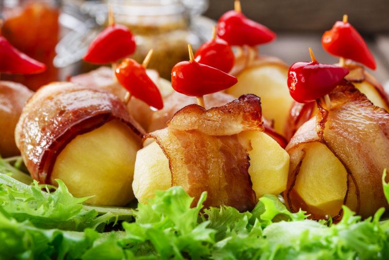 Cooked pieces of potato that have been wrapped in bacon with toothpicks