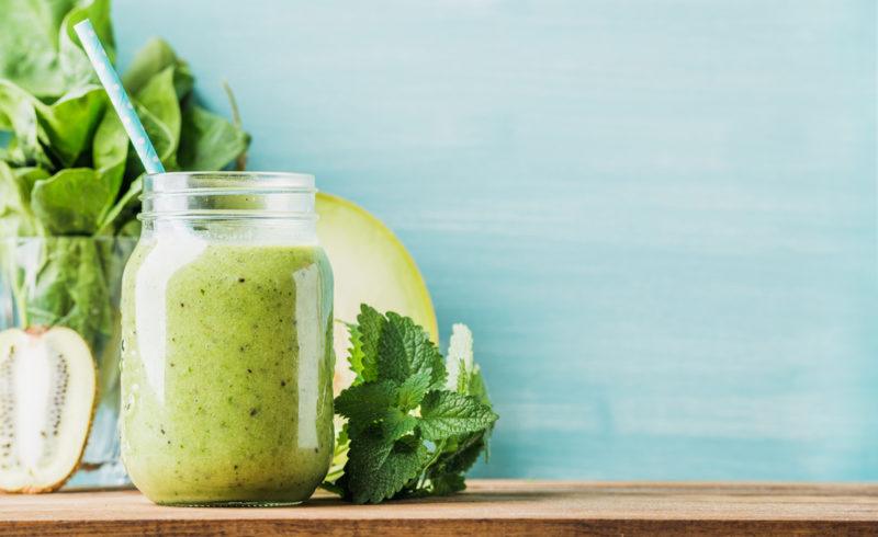 A green smoothie with the ingredients in the background