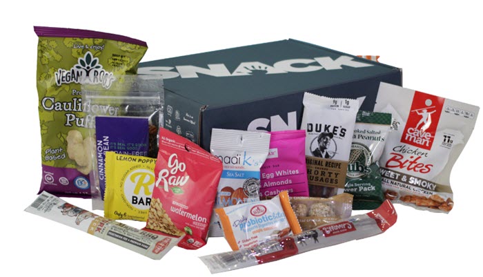 A closed green box with a variety of paleo snacks in front of it