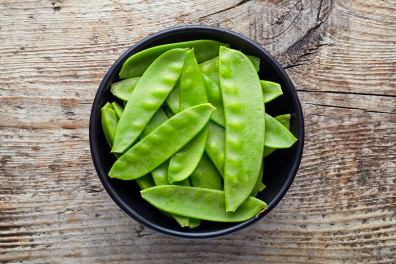 A black bowl with snow peas