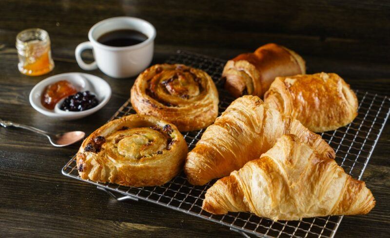 A wire frame with various French pastries, next to coffee and spreads