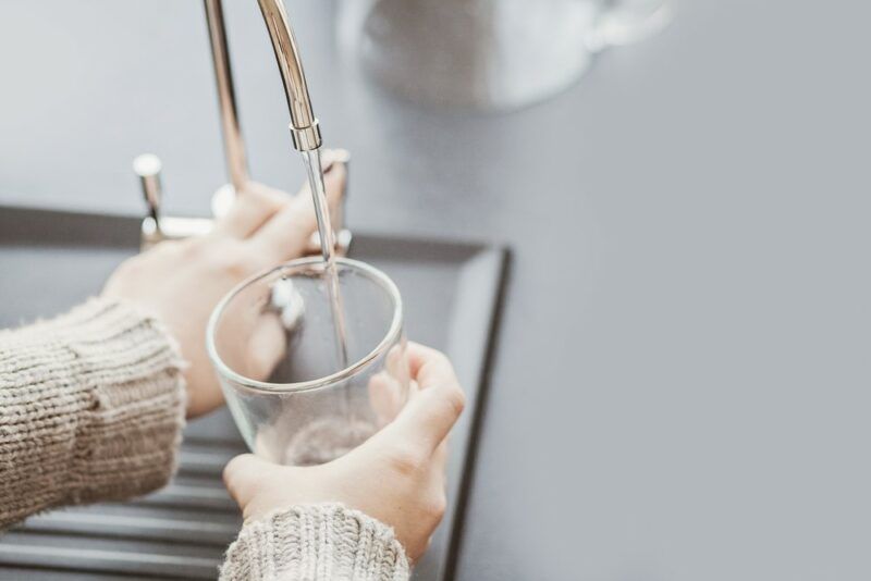 Filling a glass of filtered water from a filter in the kitchen