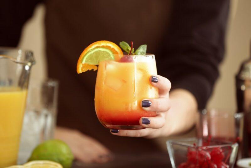 Someone holding a Kentucky sunrise cocktail with red along the bottom