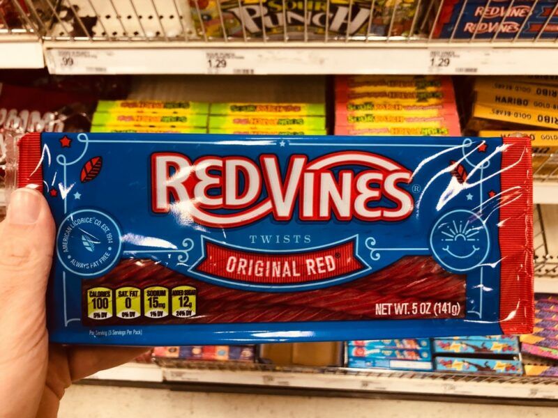 Someone holding a bag of Red Vines in a grocery store, with more treats in the background