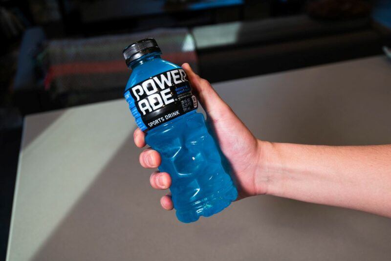 A hand clenching a blue bottle of Powerade