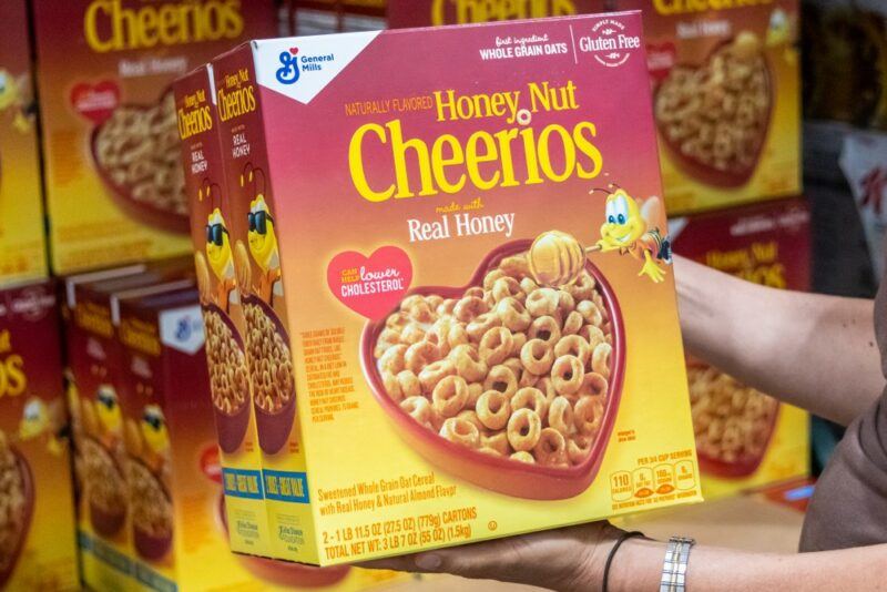 A couple of large boxes of honey nut Cheerios that someone is holding in their hand