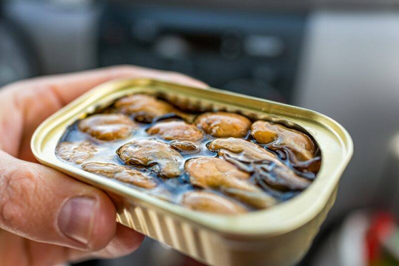 Someone holding a small can of smoked oysters