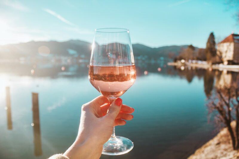 Someone holding a glass of rose up to the ocean