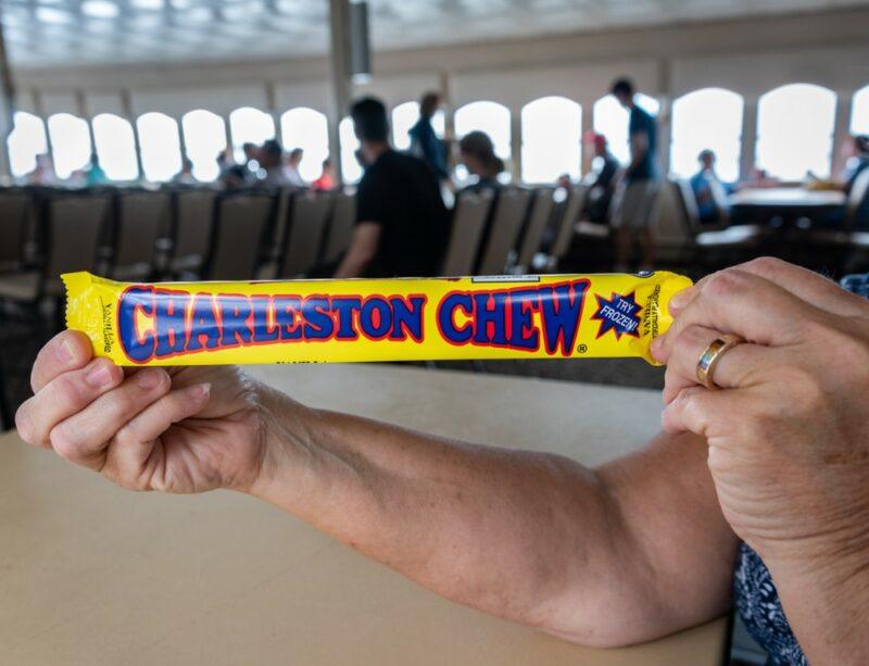 Someone holding up a large Charleston Chew in a station somewhere