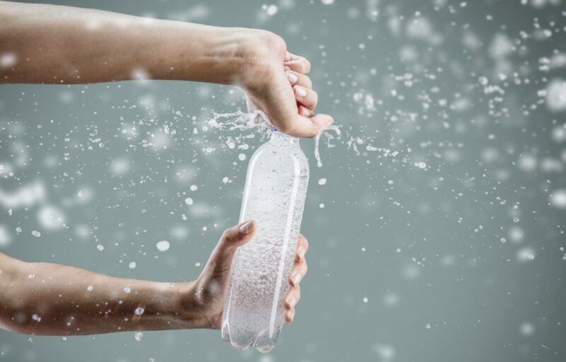 Someone opening a bottle of sparkling water, with the bubbles going everywhere