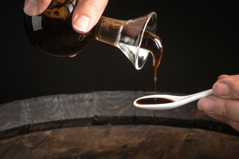 Someone pouring balsamic vinegar onto a spoon