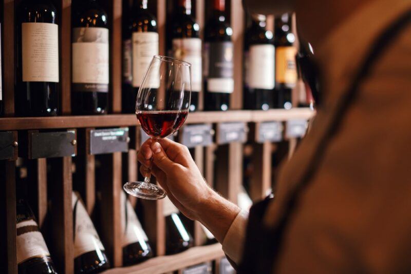 Someone holding a glass of wine in front of a selection of bottles in the store