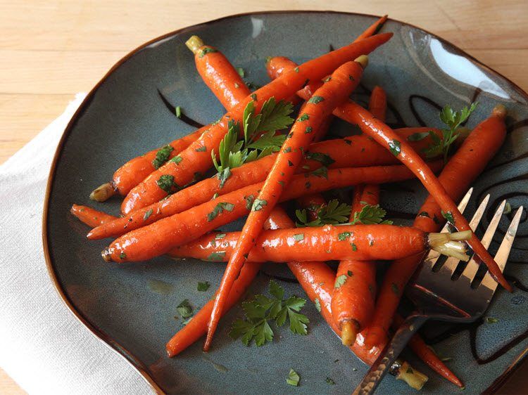 A blue plate with carrots that have been cooked in sous vide, next to a fork