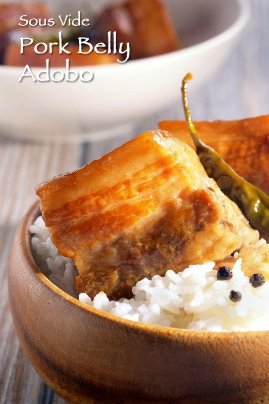 A wooden bowl containing white rice, filled with sous vide pork belly adobo. 
