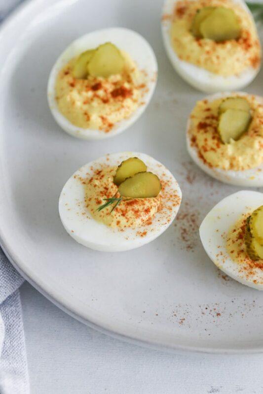 A white plate with Southern deviled eggs garnished with pickles