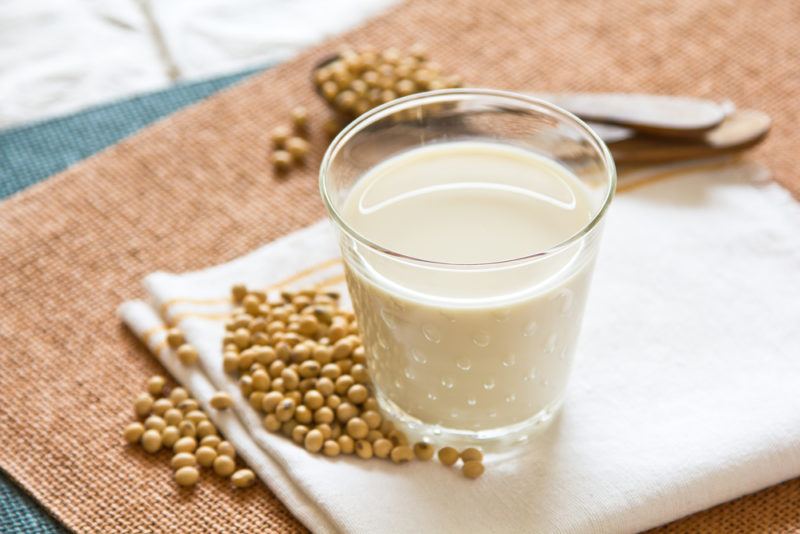 A glass of soy milk with soybeans on a table