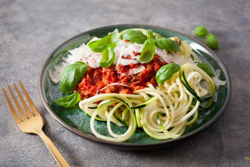 A blue-green plate with spaghetti bolognese that has been made using zoodles