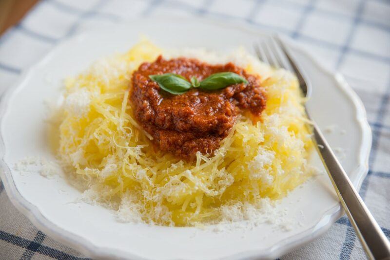 A white plate with a bolognase pasta dish made using spaghetti squash rather than pasta