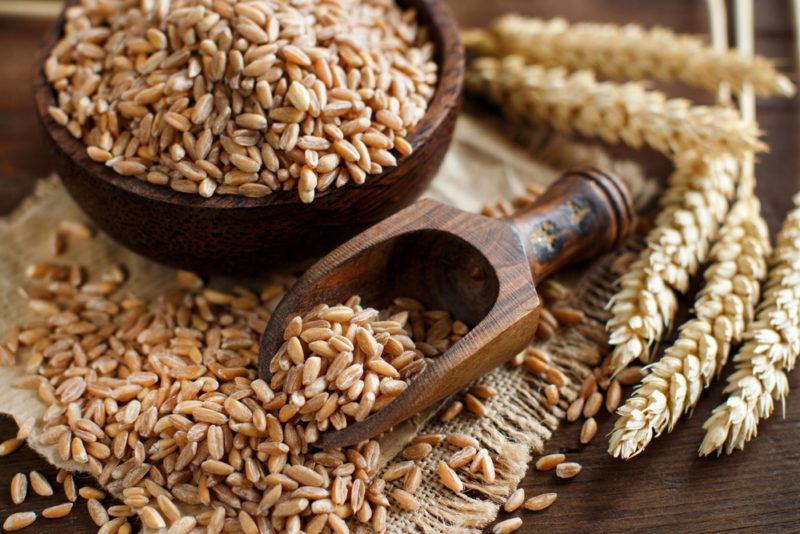 A wooden bowl and spoon containing spelt