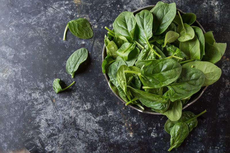 A bowl of spinach on a marble table