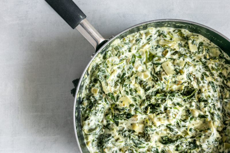 A saucepan containing spinach and artichoke dip