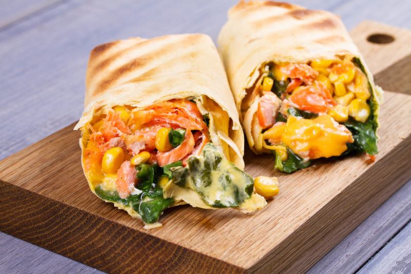 Breakfast burritos that contain spinach, salmon and a collection of other ingredients