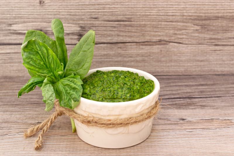 Pesto made from spinach with spinach leaves in a white bowl