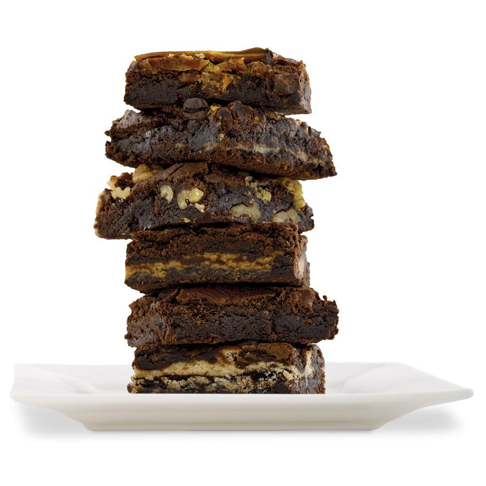 Stack of 6 brownies on a white square plate.  Flavors featured are chocolate, chocolate walnut, cookies and cream, and double chocolate