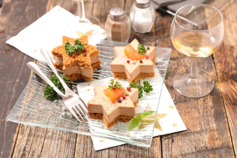 Three pieces of star shaped foie gras on a wooden table with sauternes wine