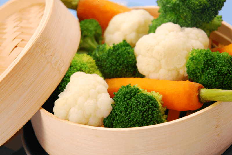 A steamer basket that contains broccoli, cauliflower, and carrots