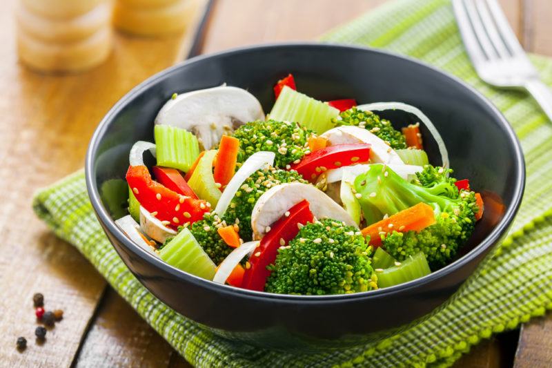 A black bowl with steamed veggies