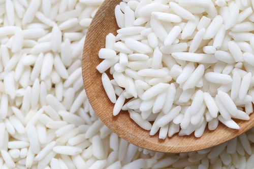 closeup image of sticky rice or glutinous rice with a wooden spoon also with raw sticky rice grains